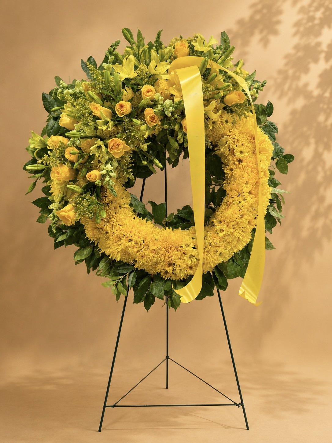Yellow sympathy wreath with a yellow ribbon on an easel stand